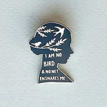 Cargar imagen en el visor de la galería, Pin esmaltado de color negro y metal plateado con la inscripción " I am no bird and no net ensnares me" sobre superficie blanca